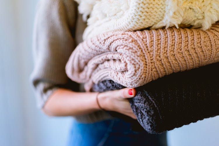 इंस्टाग्राम के लिए शरद फोटो विचार - उसके हाथों में मुड़ा हुआ स्वेटर वाली लड़की